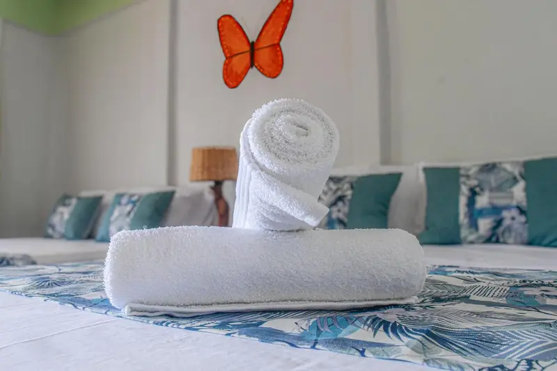 Serviettes roulées posées sur un lit décoré de motifs tropicaux.