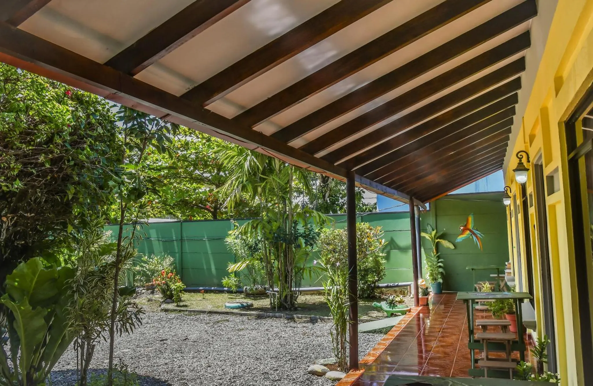 Terrasse ombragée donnant sur un jardin tropical.