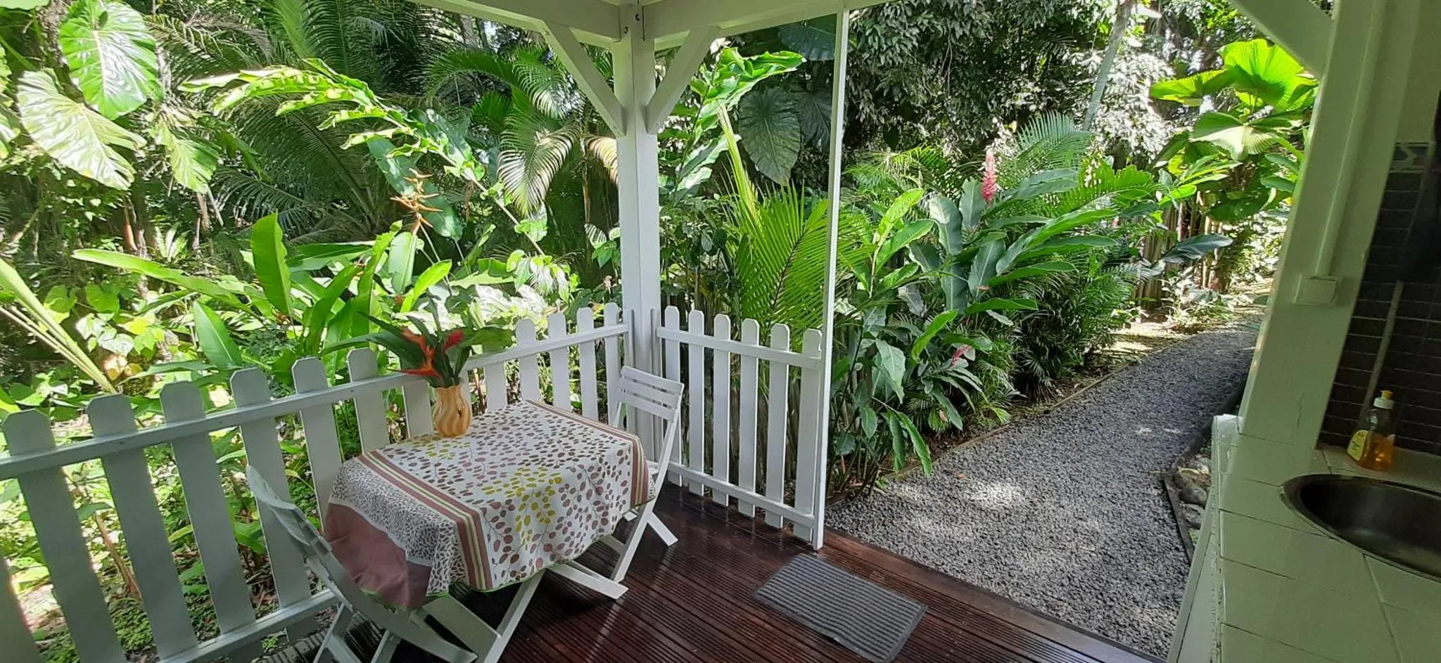 Une terrasse ombragée s'ouvre sur une végétation luxuriante.