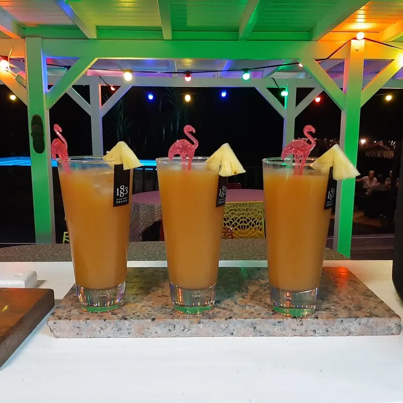 Trois verres de cocktail exotiques sont présentés sur un comptoir éclairé.