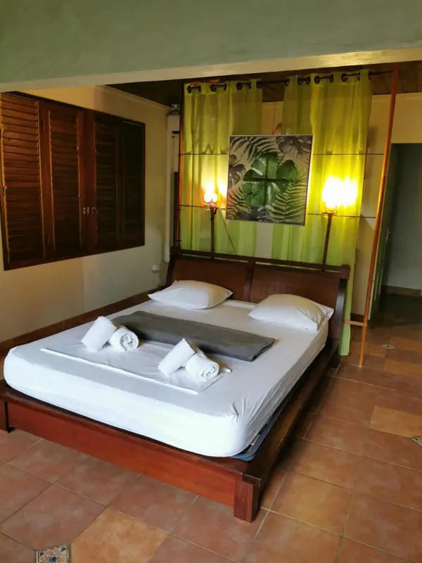 Une chambre lumineuse avec un grand lit recouvert de draps blancs et de serviettes.