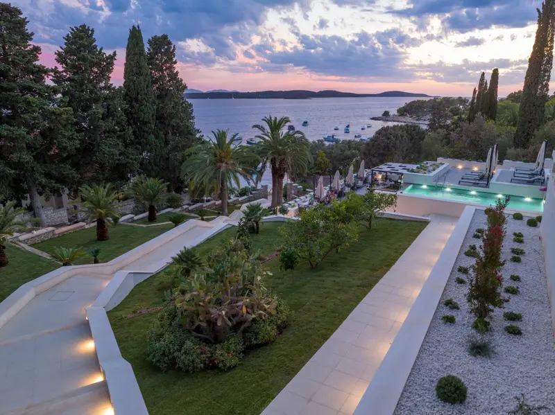 Vue aérienne d'un complexe hôtelier avec piscine et végétation luxuriante au bord de la mer.