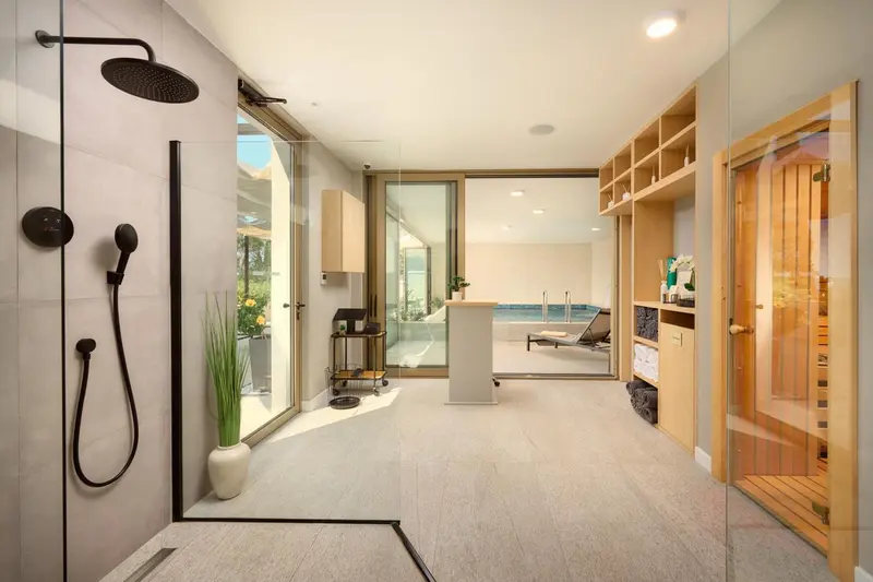 Une douche à l'italienne moderne s'ouvre sur une terrasse avec un espace détente.