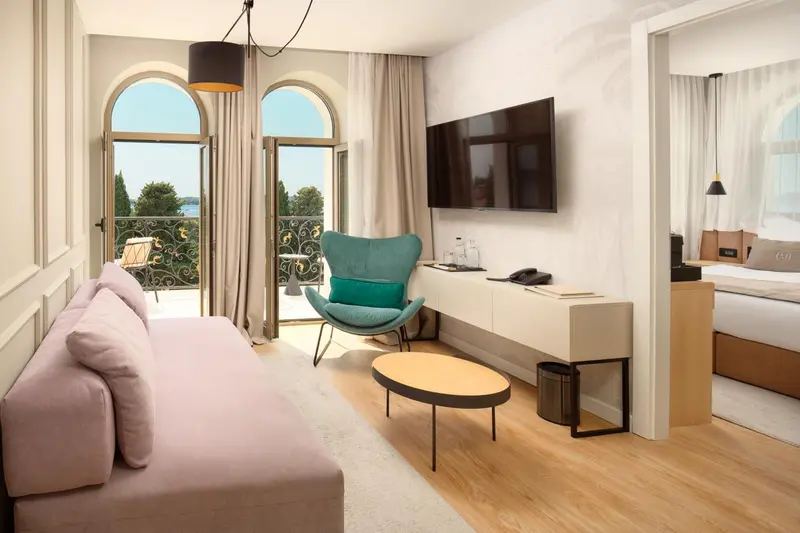 Un salon confortable avec canapé, fauteuil et table basse s'ouvre sur un balcon.