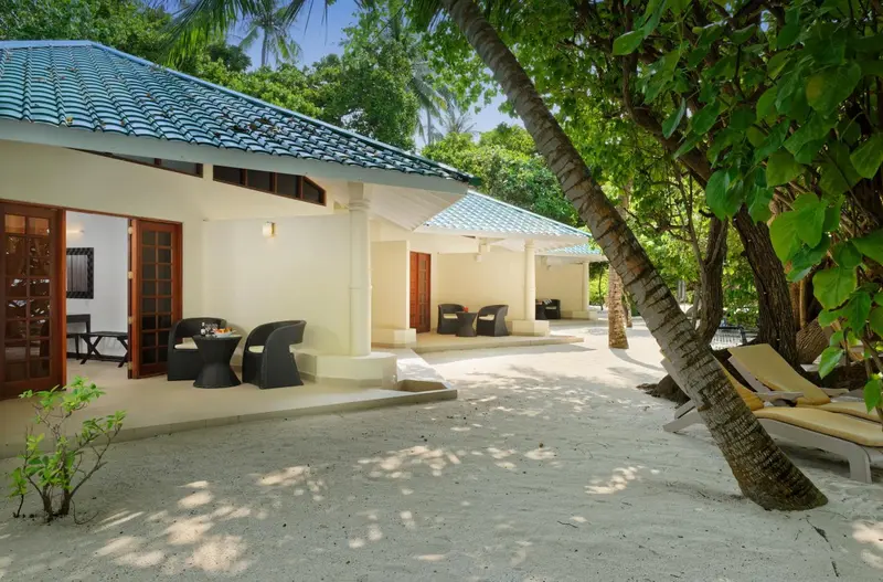 Terrasse ombragée devant des bungalows blancs.