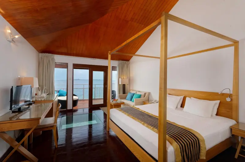 Une chambre lumineuse avec un grand lit à baldaquin et une vue sur la mer.