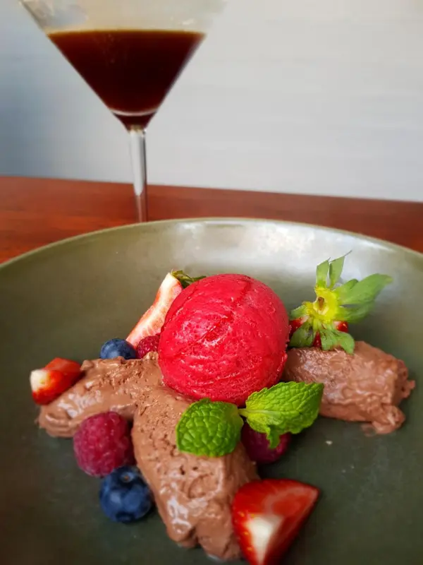 Assiette de dessert avec mousse au chocolat, sorbet aux fruits rouges et fruits frais.