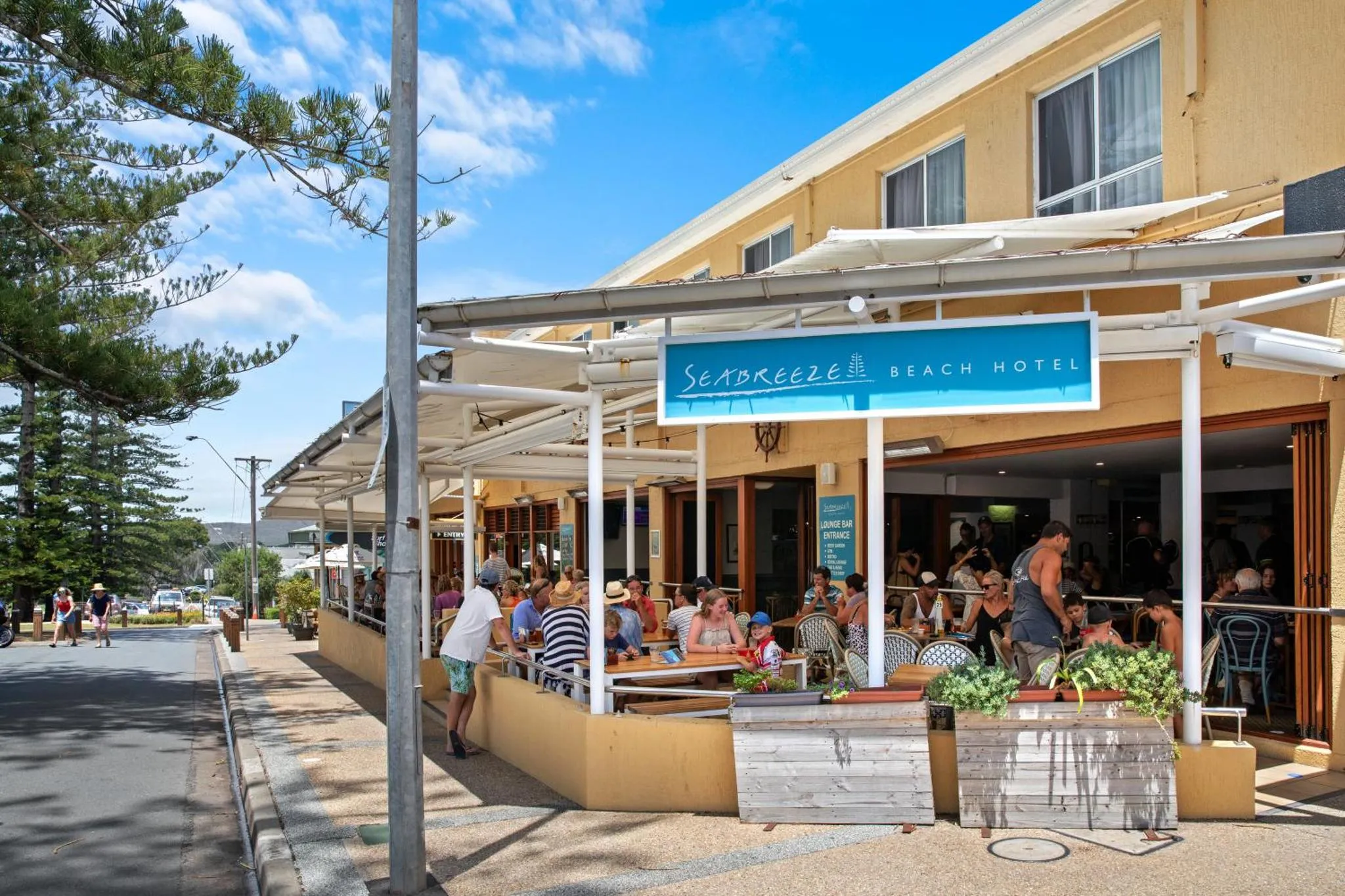 Terrasse ombragée d'un établissement avec des clients attablés.
