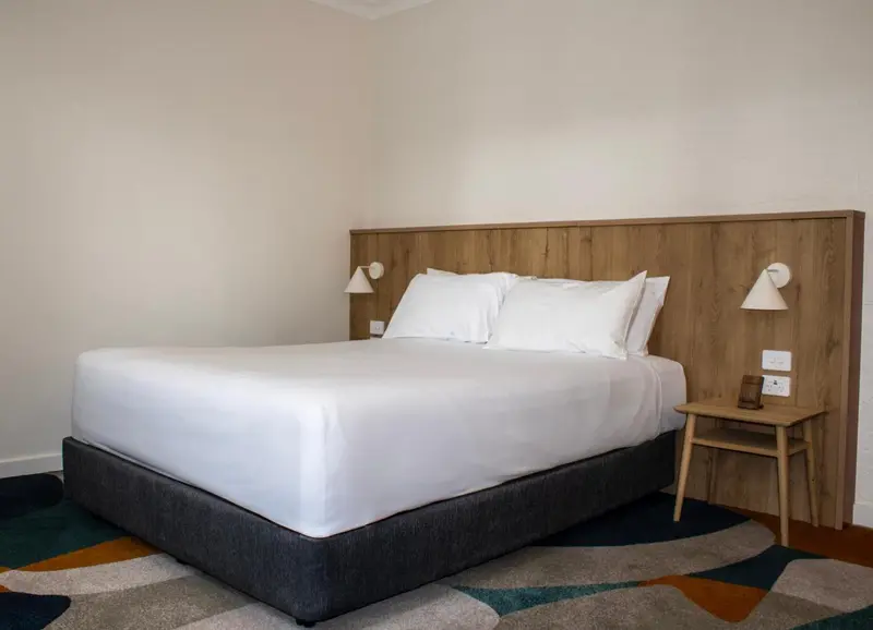 Une chambre lumineuse avec un grand lit recouvert d'une couette blanche.