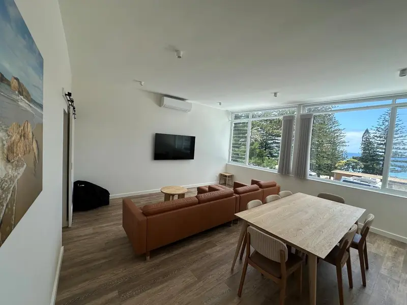 Espace de vie lumineux avec canapés et table à manger près d'une grande fenêtre.