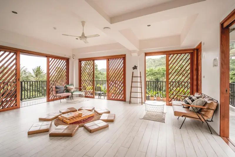 Espace de détente lumineux avec mobilier en bois et vue sur la végétation.