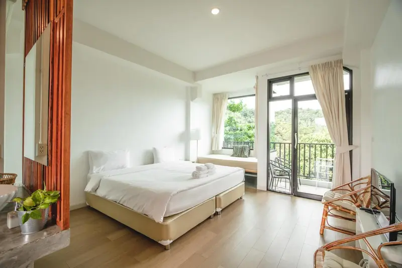 Une chambre lumineuse avec un grand lit et un accès à un balcon.