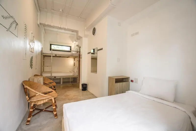 Une chambre lumineuse avec lits superposés et mobilier en rotin.