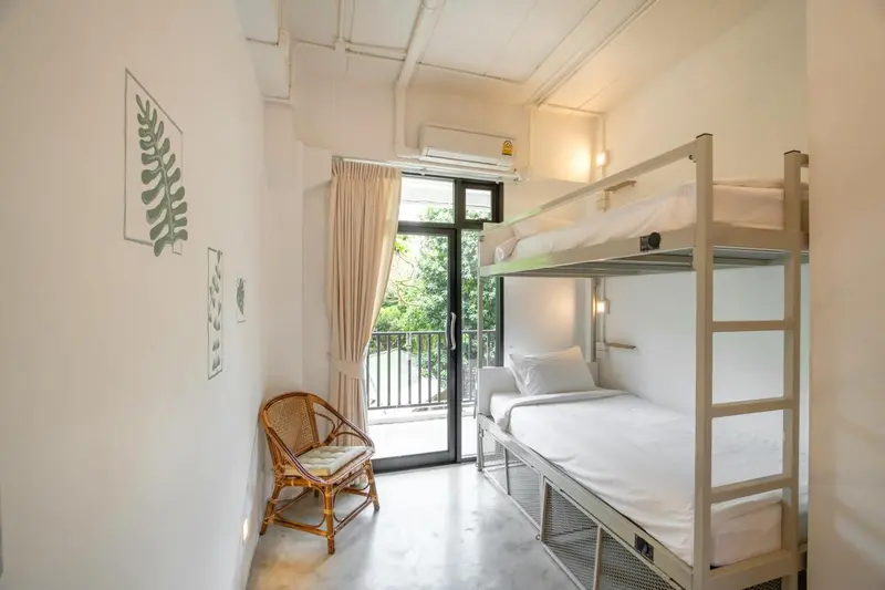 Une chambre avec un lit superposé et une fenêtre donnant sur la végétation.
