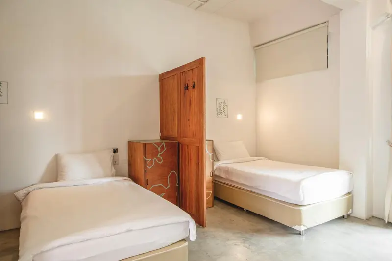 Une chambre lumineuse avec deux lits simples et une commode en bois.