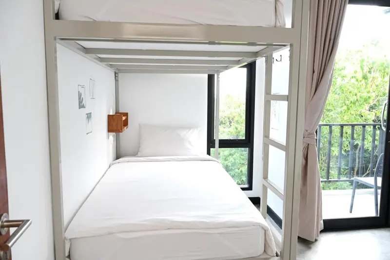 Lit simple dans un espace lumineux avec vue sur la végétation.