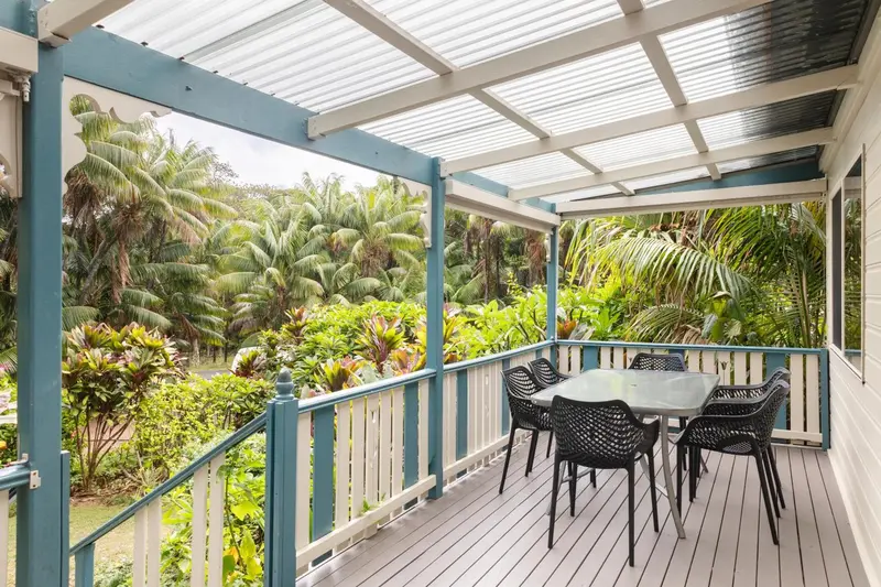 Terrasse en bois avec mobilier de jardin et végétation luxuriante en arrière-plan.