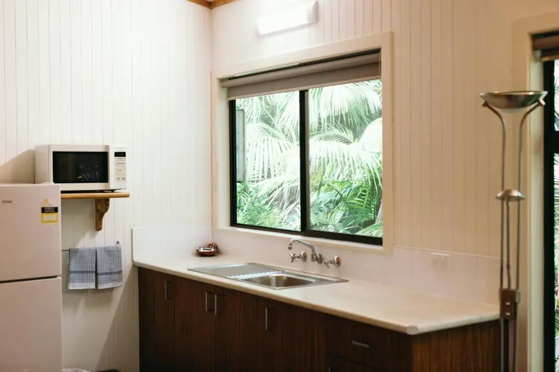 Une kitchenette lumineuse avec un évier et un micro-ondes.
