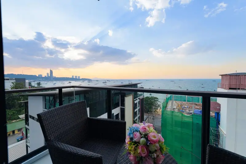 Terrasse avec mobilier et vue sur la mer au coucher du soleil.