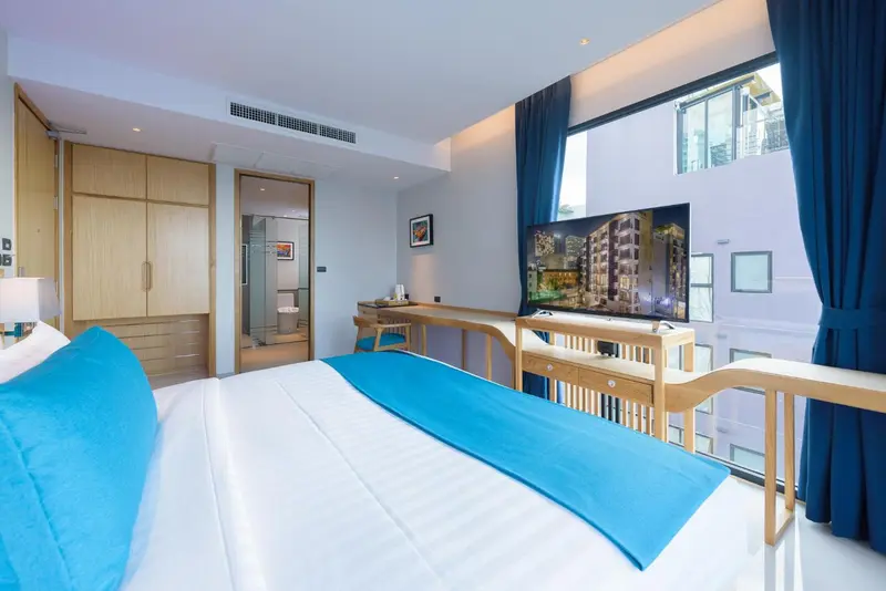 Une chambre lumineuse avec un grand lit et une télévision murale.