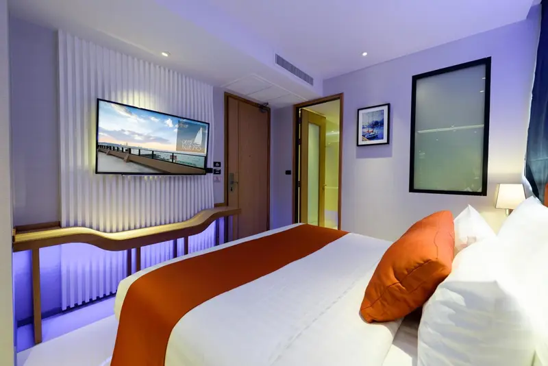 Une chambre lumineuse avec un grand lit et une télévision murale.