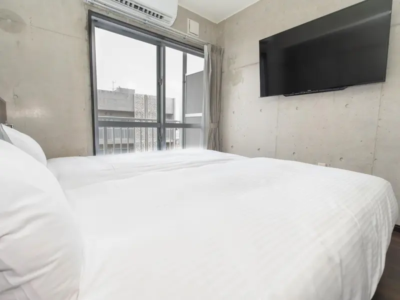 Une chambre lumineuse avec un grand lit et une vue sur la ville.