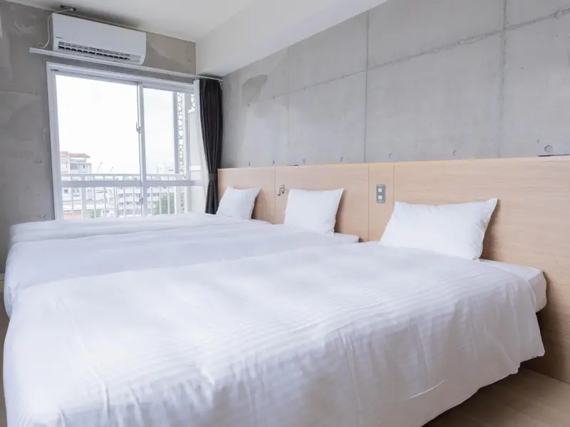 Une chambre lumineuse avec deux lits simples et une fenêtre.