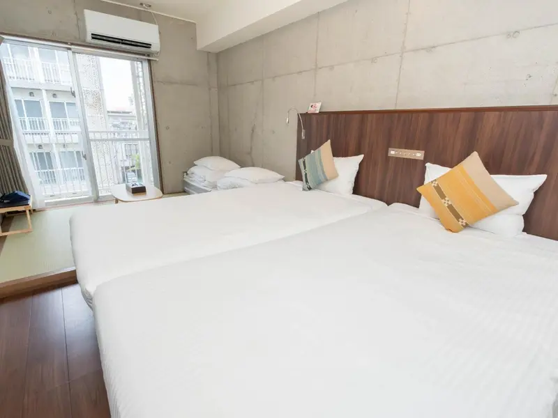 Chambre lumineuse avec deux lits simples et une fenêtre.