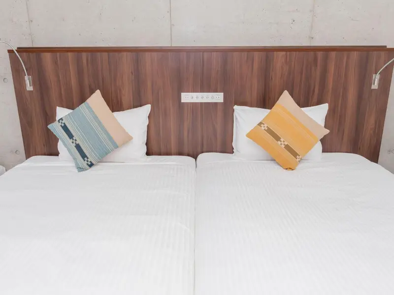 Un lit double avec des oreillers décoratifs est présenté dans une chambre lumineuse.