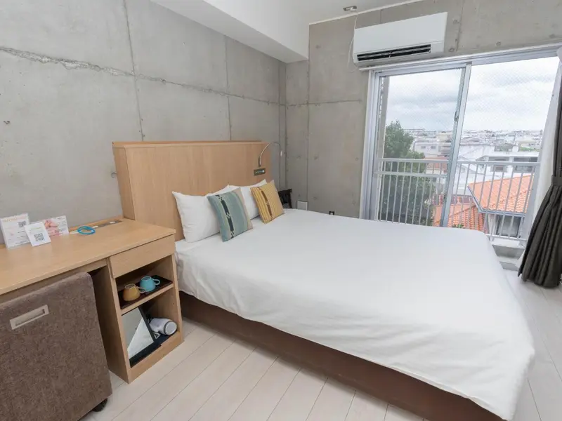 Une chambre lumineuse avec un lit double et un balcon.