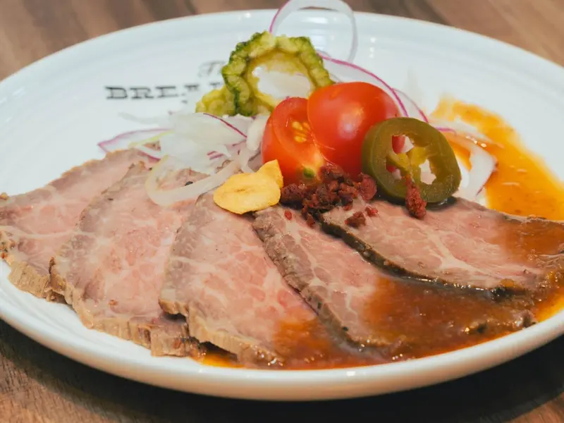 Assiette de viande tranchée accompagnée de légumes et d'une sauce.