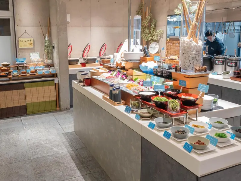 Un buffet propose une variété de plats et de salades dans un espace lumineux.