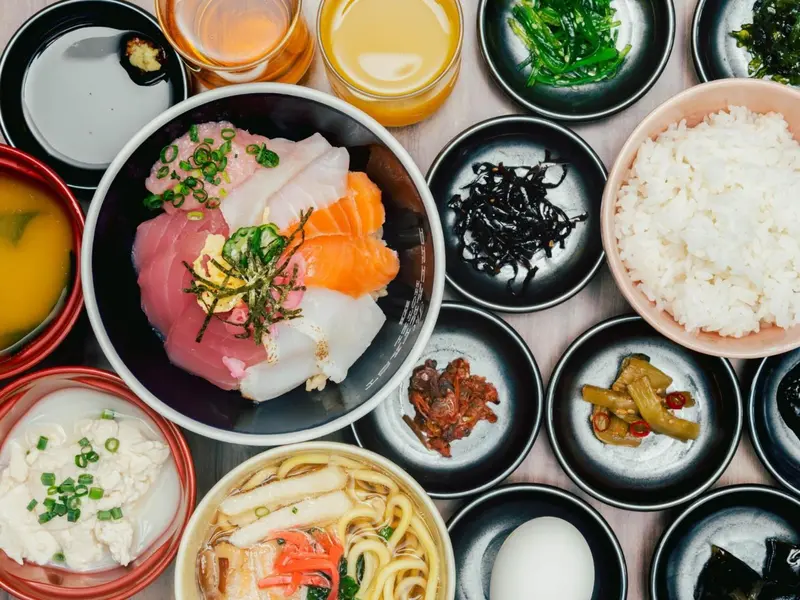 Assortiment de petits plats japonais servis dans des coupes noires et colorées.