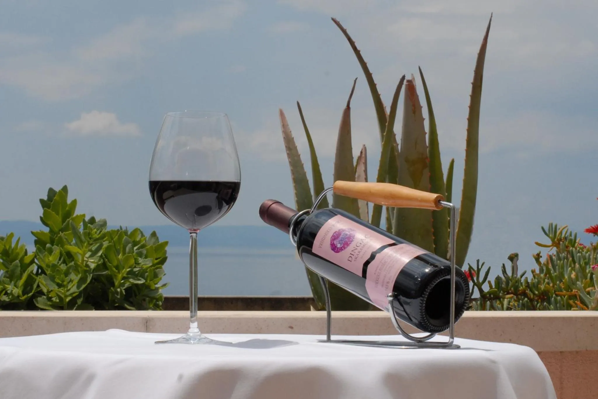 Une bouteille de vin et un verre sur une table avec vue sur la mer.