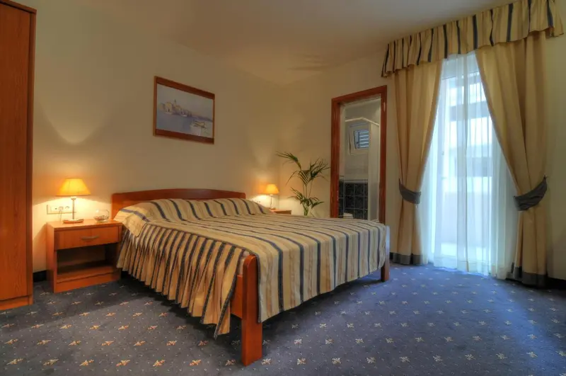 Une chambre lumineuse avec un lit double et un rideau transparent.