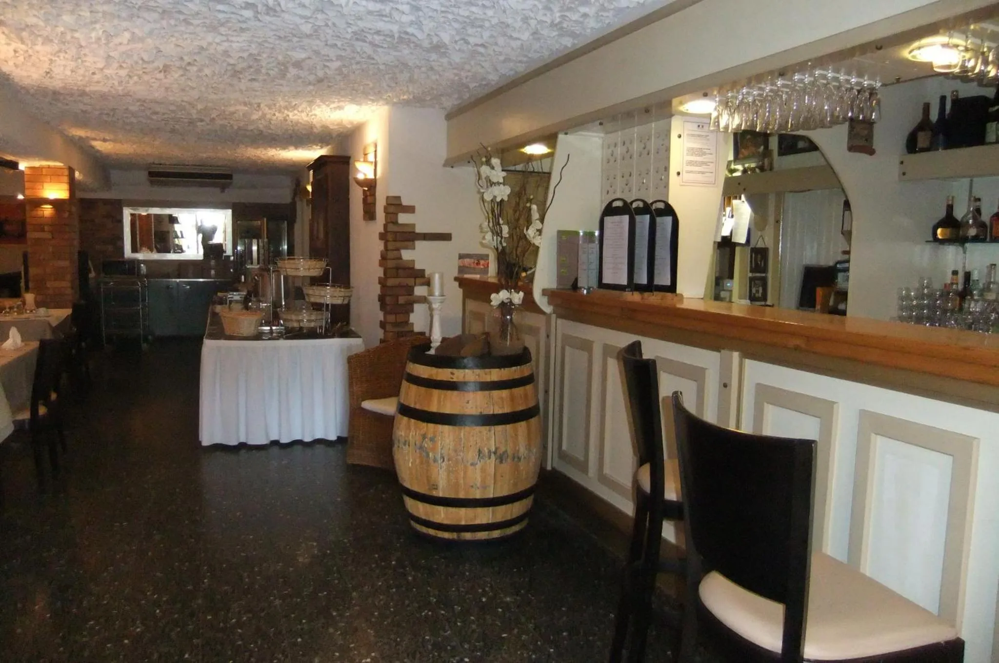 Une salle de restaurant avec un comptoir de bar et des tables nappées.