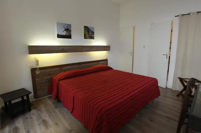 Une chambre avec un grand lit recouvert d'une courtepointe rouge et un tableau au mur.