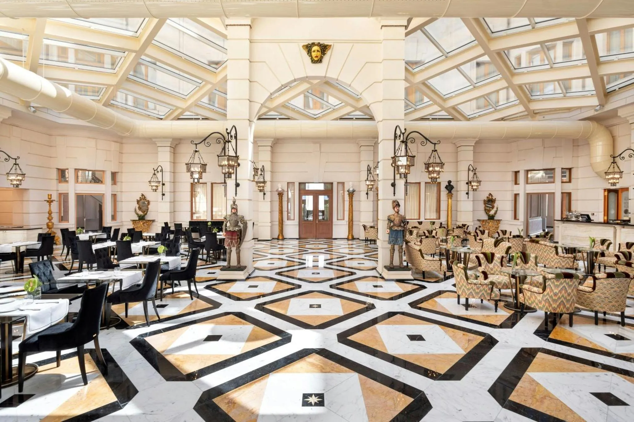 Vaste salle lumineuse avec un sol à motifs géométriques et des tables de restaurant disposées en rangées.