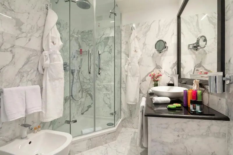 Une salle de bain lumineuse avec une douche à l'italienne et un lavabo sur un plan de travail sombre.