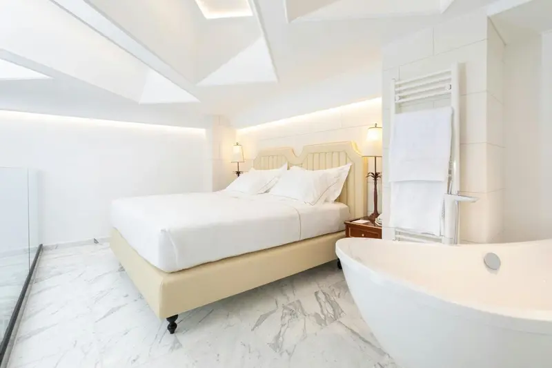 Une chambre lumineuse avec un grand lit et une baignoire.