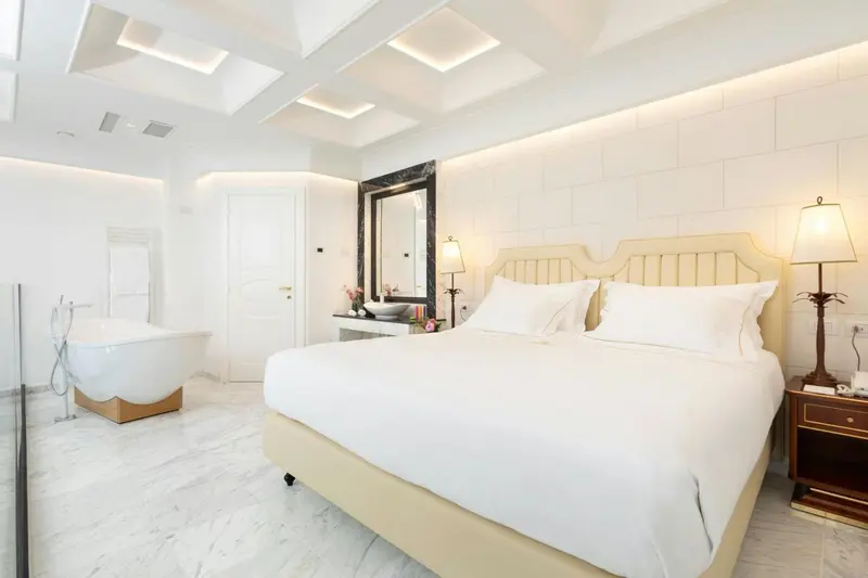 Une chambre lumineuse avec un grand lit et une baignoire.