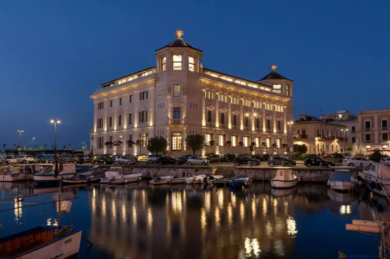 Bâtiment illuminé au bord d'un port de plaisance au crépuscule.