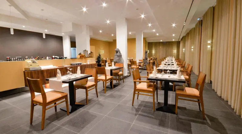 Une salle lumineuse avec des tables dressées pour un repas.