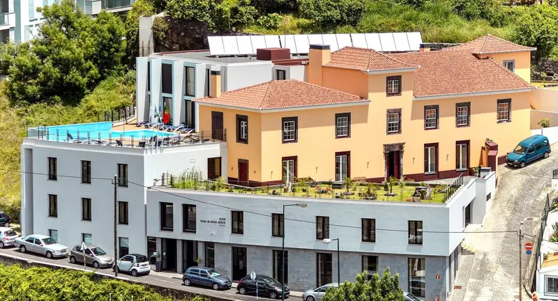 Bâtiment à plusieurs niveaux avec toits en tuiles et piscine sur le toit.