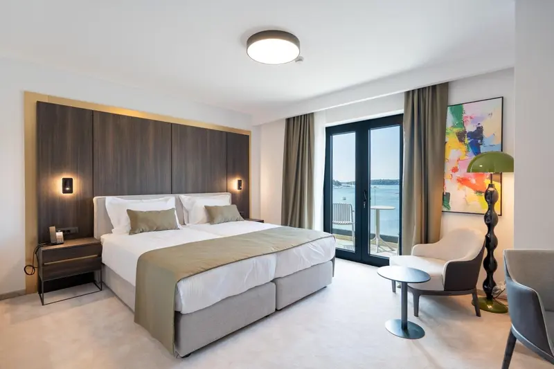 Une chambre lumineuse avec un grand lit et un accès à un balcon.