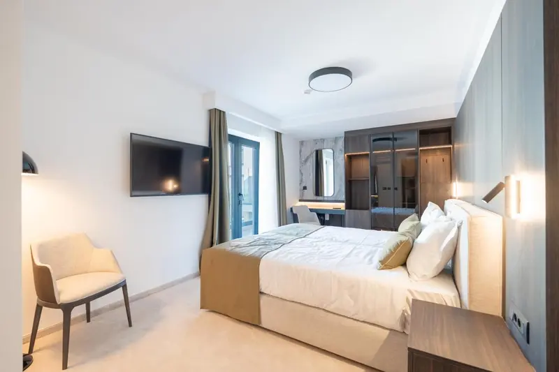 Chambre lumineuse avec un grand lit et un fauteuil.
