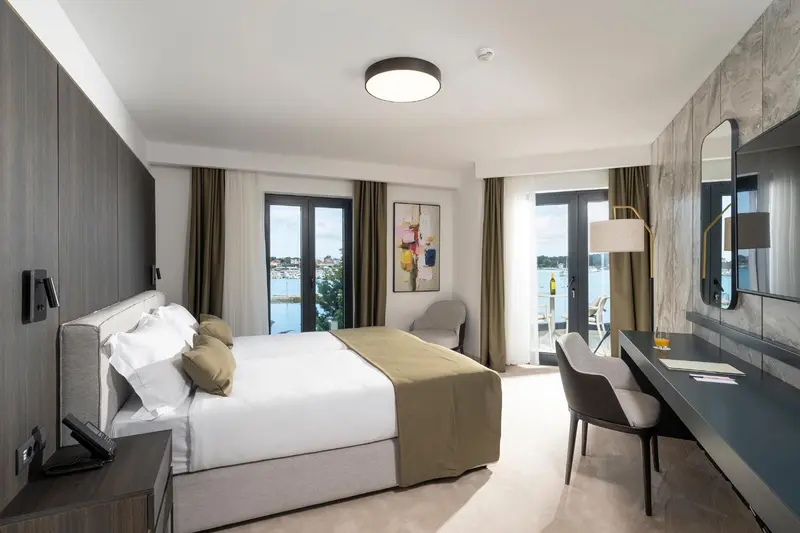 Chambre lumineuse avec un grand lit et un bureau près d'une fenêtre.