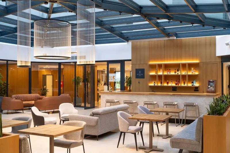 Espace de détente avec canapés et tables basses près d'un bar lumineux.
