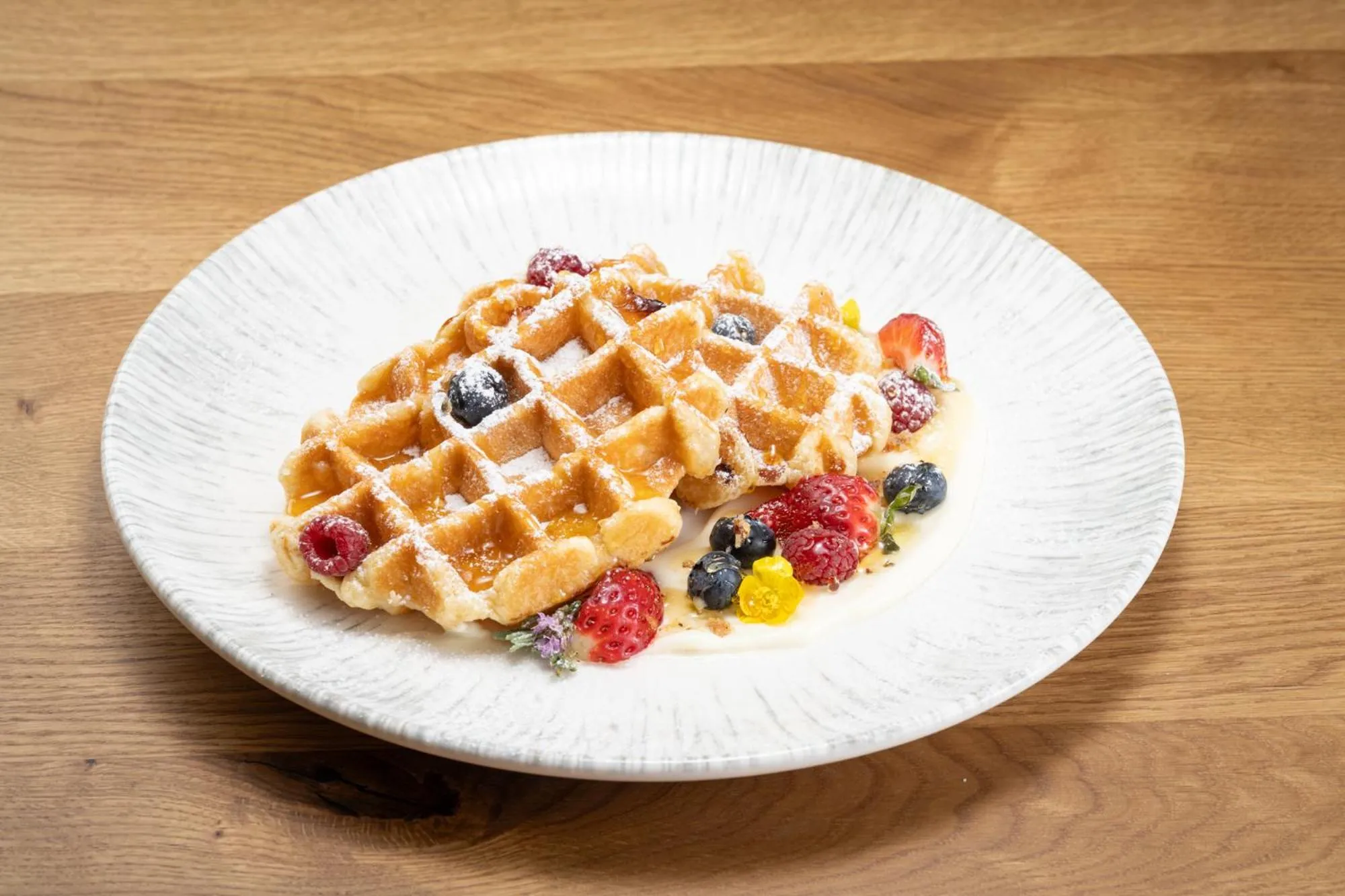 Assiette de gaufres garnies de fruits frais et de sucre glace.
