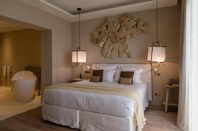 Une chambre lumineuse avec un grand lit et une baignoire.